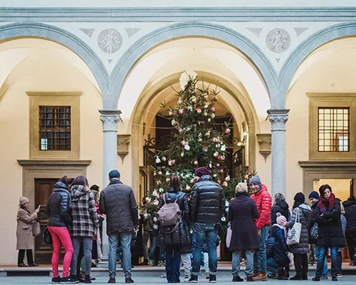 genitori e bambini davanti all'albero di Natale nel Cortile degli Uomini dell'Istituto degli Innocenti